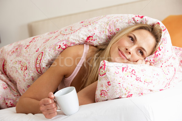 Pretty Woman Snuggled Under Duvet With Hot Drink Stock photo © monkey_business