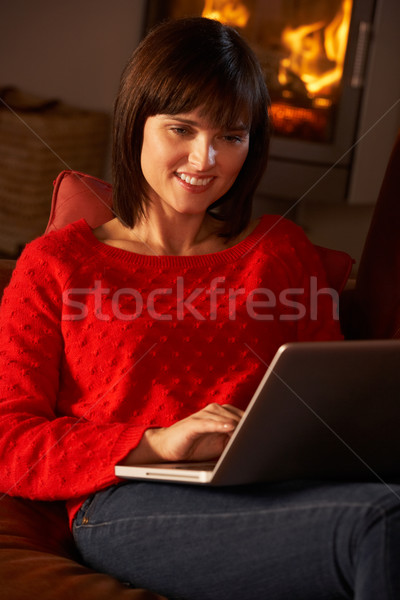 Middle Aged Woman Using Laptop Computer By Cosy Log Fire Stock photo © monkey_business