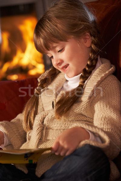 Young Girl Sitting On Sofa And Reading Book By Cosy Log Fire Stock photo © monkey_business