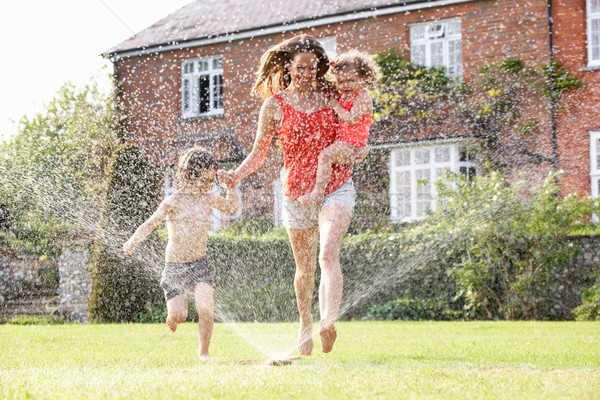 Mutter zwei Kinder läuft Garten Sprinkler Stock foto © monkey_business
