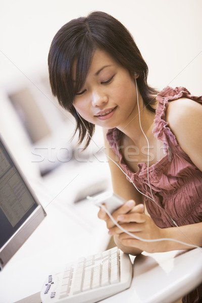 Woman in computer room listening to MP3 player Stock photo © monkey_business