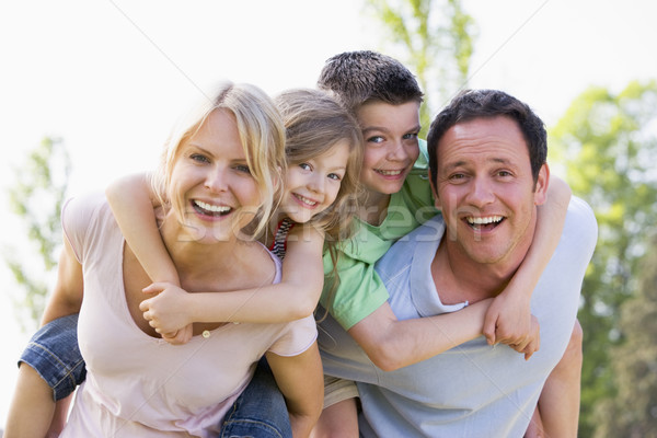 Couple giving two young children piggyback rides smiling Stock photo © monkey_business