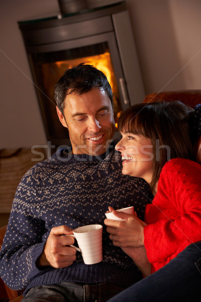 Middle Aged Couple Sitting On Sofa By Cosy Log Fire With Hot Dri Stock photo © monkey_business