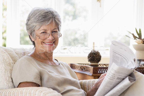 Stock photo: Woman in living room reading newspaper smiling
