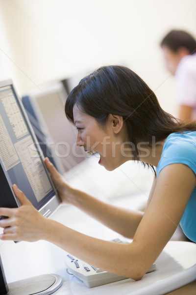 Woman in computer room holding monitor and smiling Stock photo © monkey_business