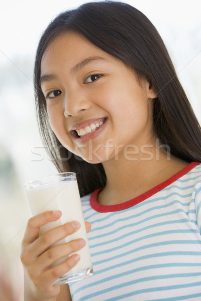 Young girl indoors drinking milk smiling Stock photo © monkey_business