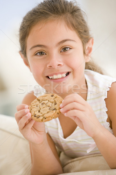 Jong meisje eten cookie woonkamer glimlachend meisje Stockfoto © monkey_business