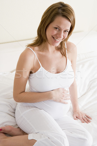 Stock photo: Pregnant woman sitting in bed smiling