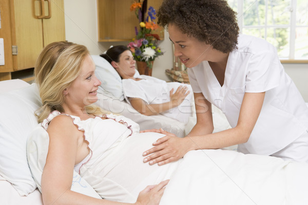 Stock photo: Nurse checking pregnant woman's belly and smiling