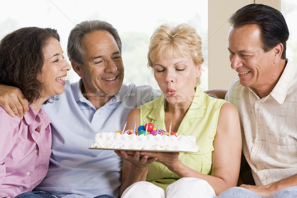 Two couples in living room smiling with woman blowing out candle Stock photo © monkey_business