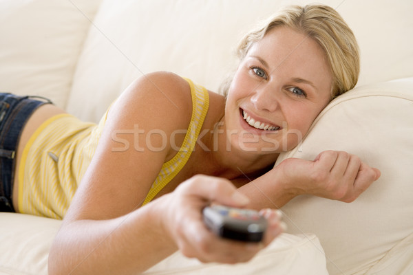 Woman in living room holding remote control smiling Stock photo © monkey_business