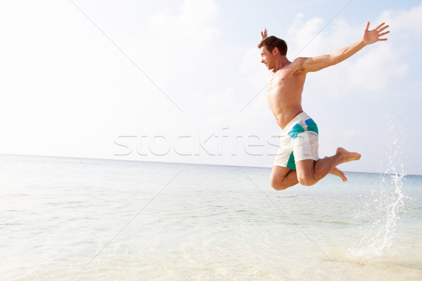 Man Jumping In The Air On Tropical Beach Stock photo © monkey_business