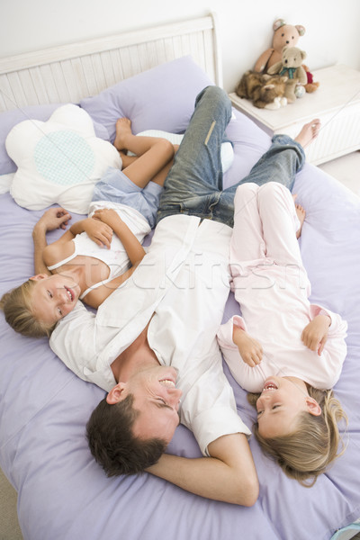 Man lying in bed with two young girls smiling Stock photo © monkey_business