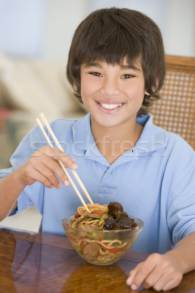 Stock photo: Young boy in dining room eating chinese food smiling