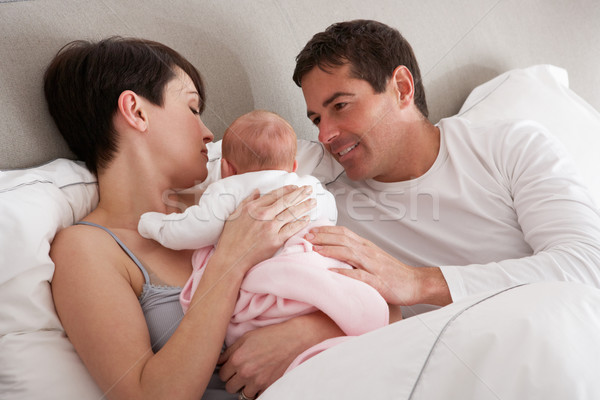 Stock photo: Parents Cuddling Newborn Baby In Bed At Home
