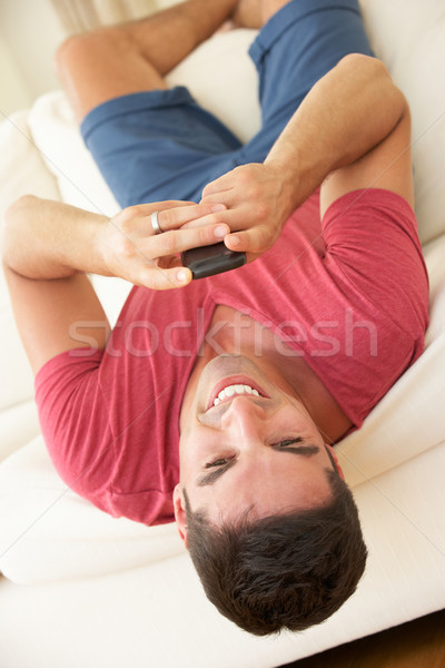 Férfi fejjel lefelé kanapé küldés szöveges üzenet férfiak Stock fotó © monkey_business