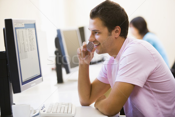 Man in computer room using cellular phone and smiling Stock photo © monkey_business