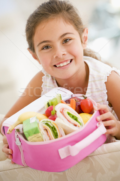 Young girl holding packed lunch in living room smiling Stock photo © monkey_business