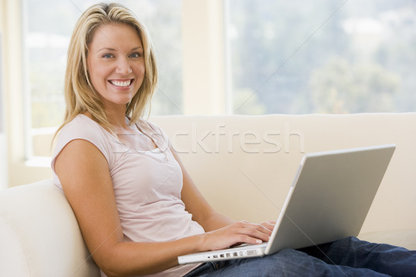 Сток-фото: женщину · гостиной · используя · ноутбук · улыбающаяся · женщина · улыбаясь · компьютер