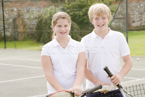 Stock photo: Two young friends with rackets on tennis court smiling