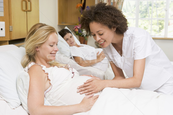 Nurse checking pregnant woman's belly and smiling Stock photo © monkey_business