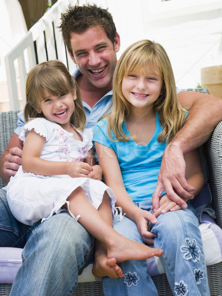 Stock photo: Man and two young girls sitting on patio smiling