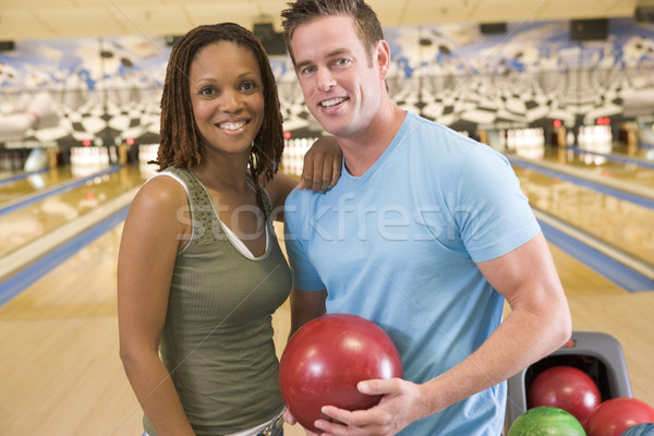 Couple in bowling alley holding ball and smiling Stock photo © monkey_business