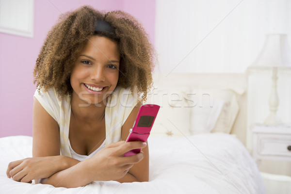 Stock photo: Teenage Girl Lying On Bed Using Mobile Phone 