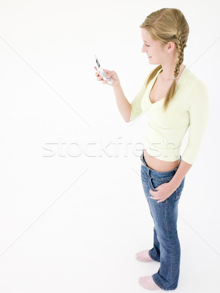 Stock photo: Teenage girl holding cellular phone and smiling