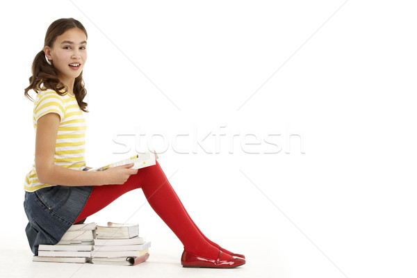 Stock photo: Young Girl Sitting On Pile Of Books Reading
