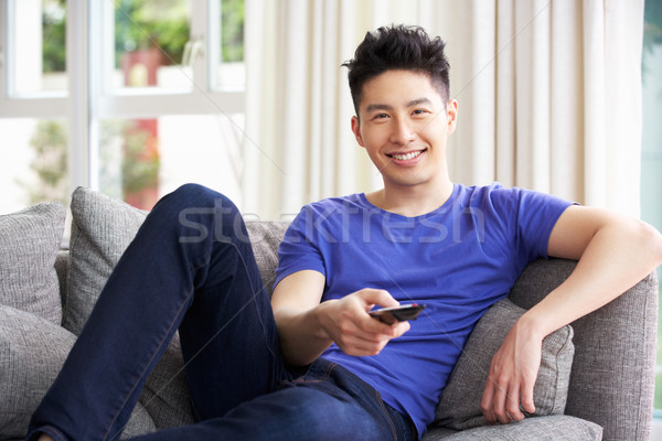 Young Chinese Man Sitting And Watching TV On Sofa At Home Stock photo © monkey_business