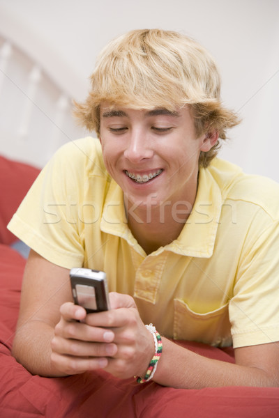 Tizenéves fiú ágy mobiltelefon otthon hálószoba póló Stock fotó © monkey_business