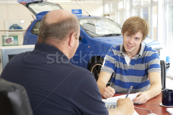 Young man filling in paperwork in car showroom Stock photo © monkey_business