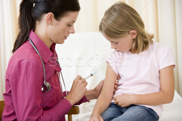 Doctor giving needle to young girl in exam room Stock photo © monkey_business