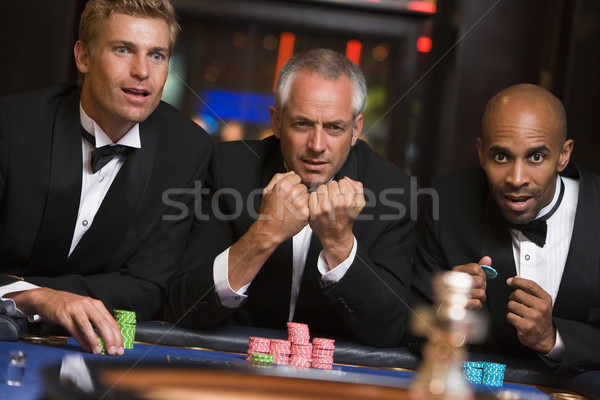 Stock photo: Group of male friends gambling at roulette table