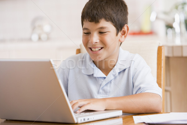 Young boy in kitchen with laptop and paperwork smiling Stock photo © monkey_business