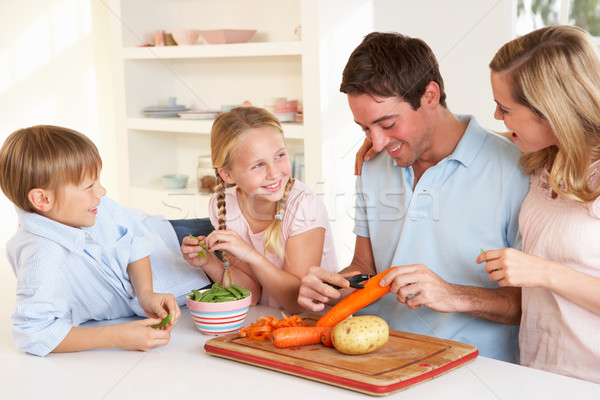 Stock photo: Happy family peeling vegetables in kitchen