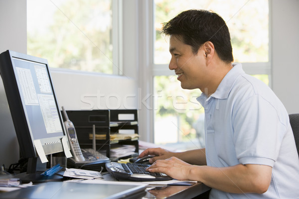 Man in home office using computer and smiling Stock photo © monkey_business