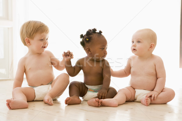Three babies sitting indoors holding hands Stock photo © monkey_business