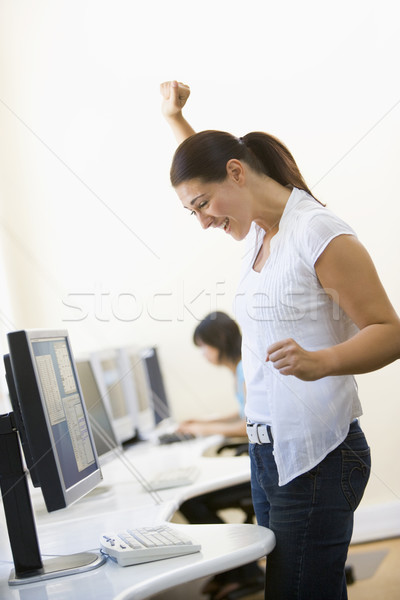 Woman standing in computer room cheering and smiling Stock photo © monkey_business
