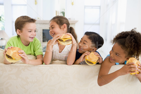 Four young children eating cheeseburgers in living room smiling Stock photo © monkey_business