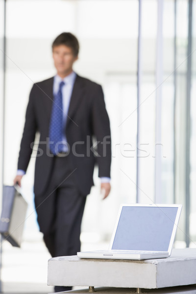 Laptop sitting in office lobby with businessman walking in Stock photo © monkey_business