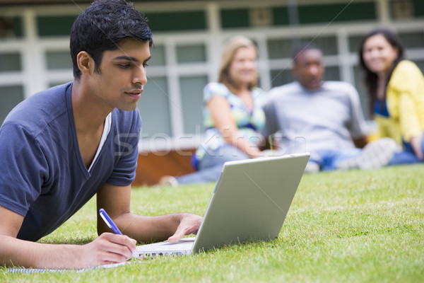 Photo stock: Jeune · homme · utilisant · un · ordinateur · portable · campus · pelouse · autre · élèves