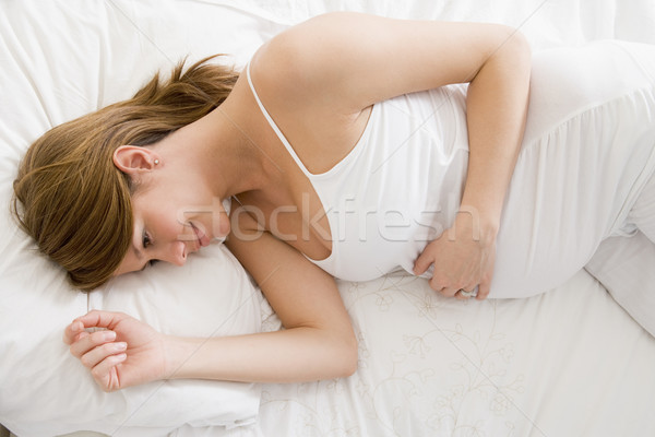 Stock photo: Pregnant woman lying in bed smiling