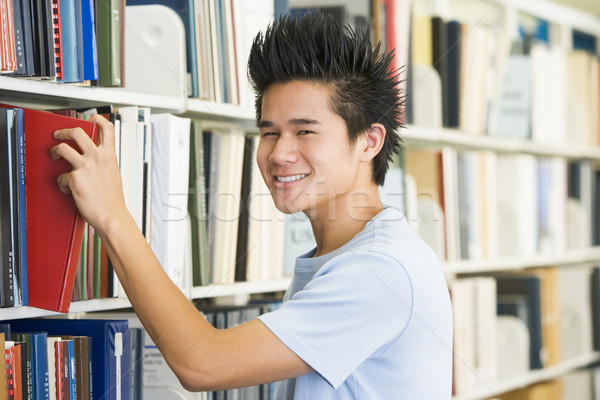 Stock photo: University student selecting book from library shelf