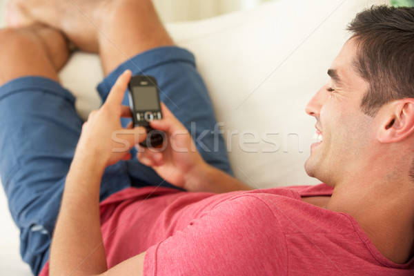 Férfi megnyugtató kanapé küldés szöveges üzenet férfiak Stock fotó © monkey_business