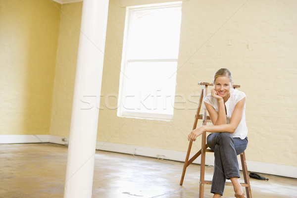 Woman sitting on ladder in empty space smiling Stock photo © monkey_business