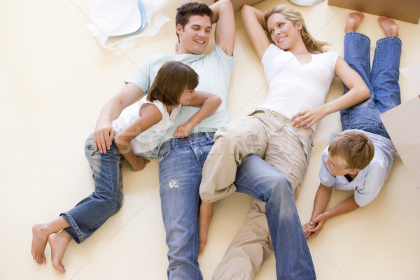 Family lying on floor by open boxes in new home smiling Stock photo © monkey_business
