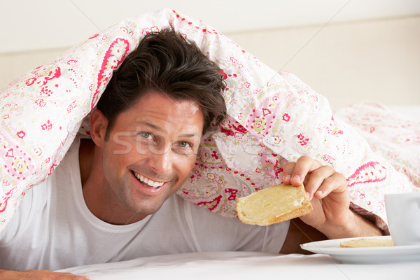 Man Snuggled Under Duvet Eating Breakfast Stock photo © monkey_business