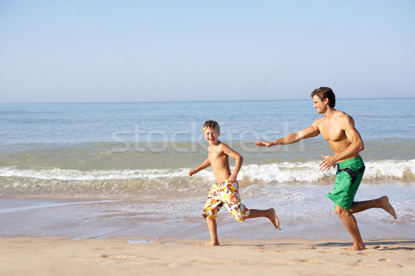 Father chasing young boy on beach Stock photo © monkey_business